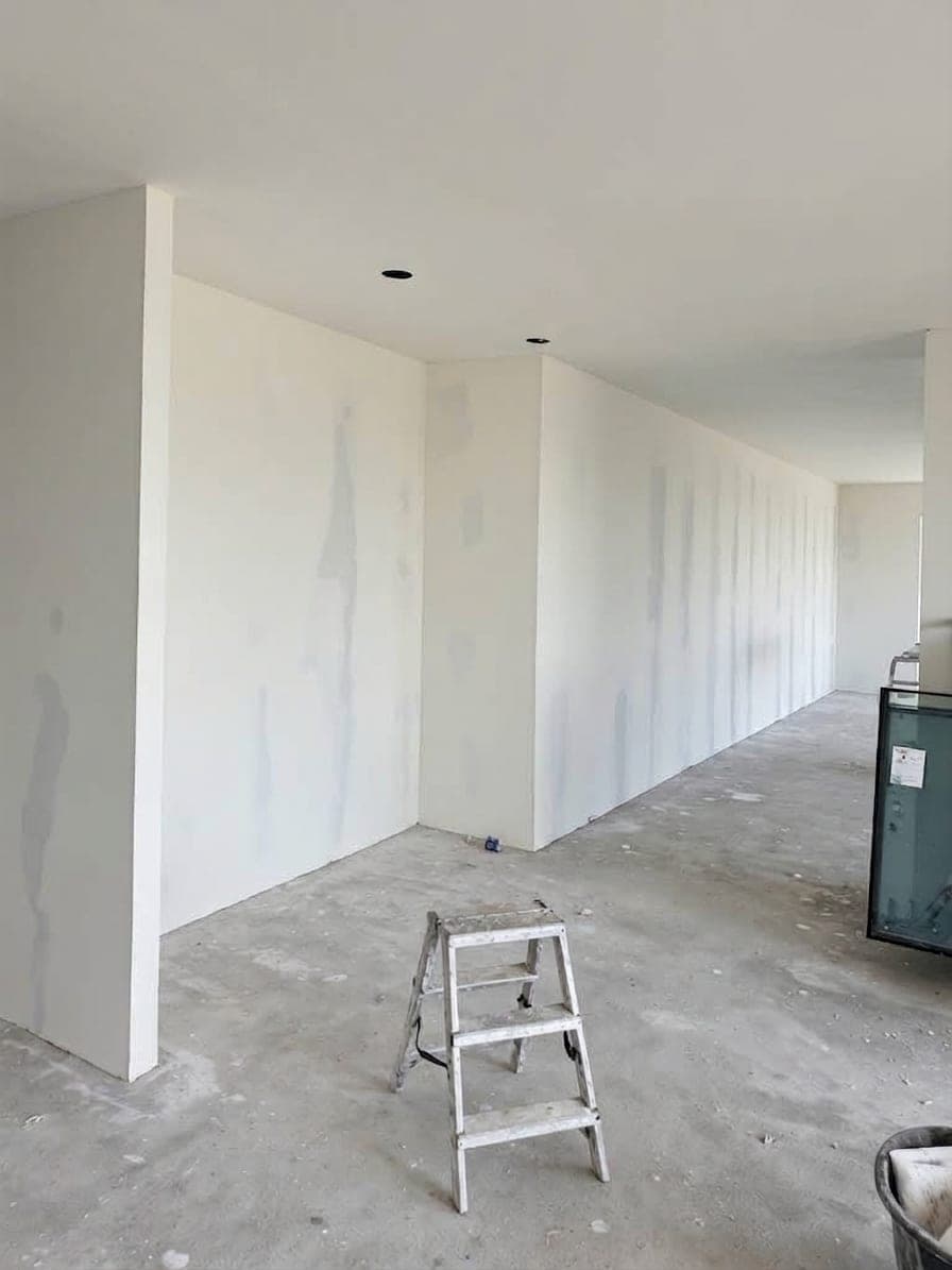 Lange wand in de woonruimte met gevulde naden, trapje op de betonvloer