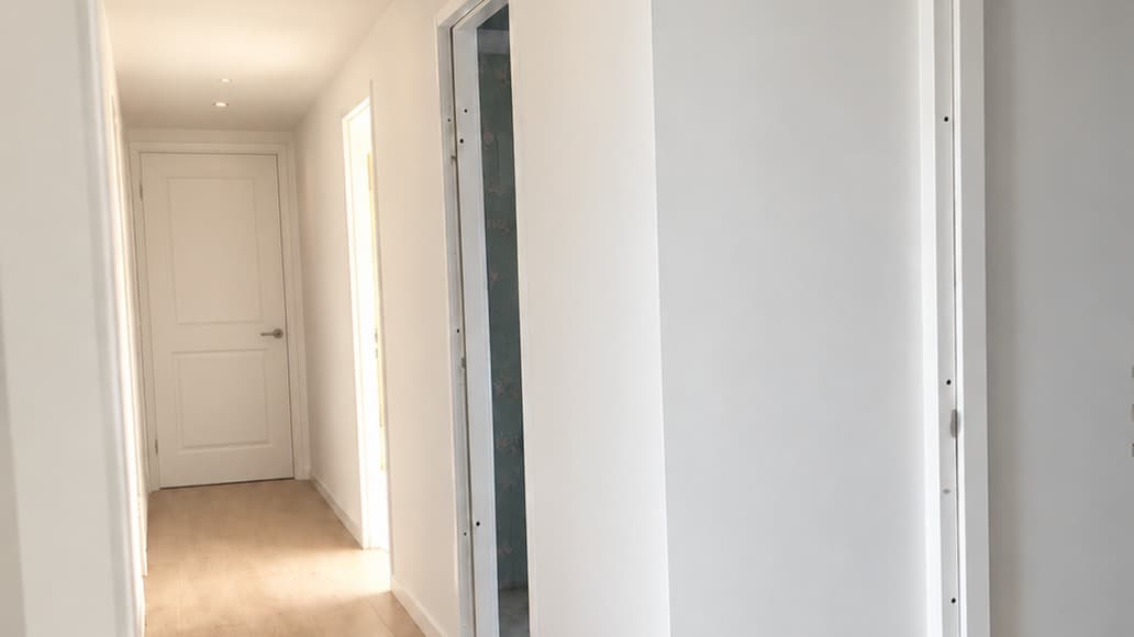 Opgeleverde hal met glad gestucte wanden en plafond en een deur aan het einde